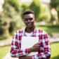 African American college student with laptop in the sunny day on the street